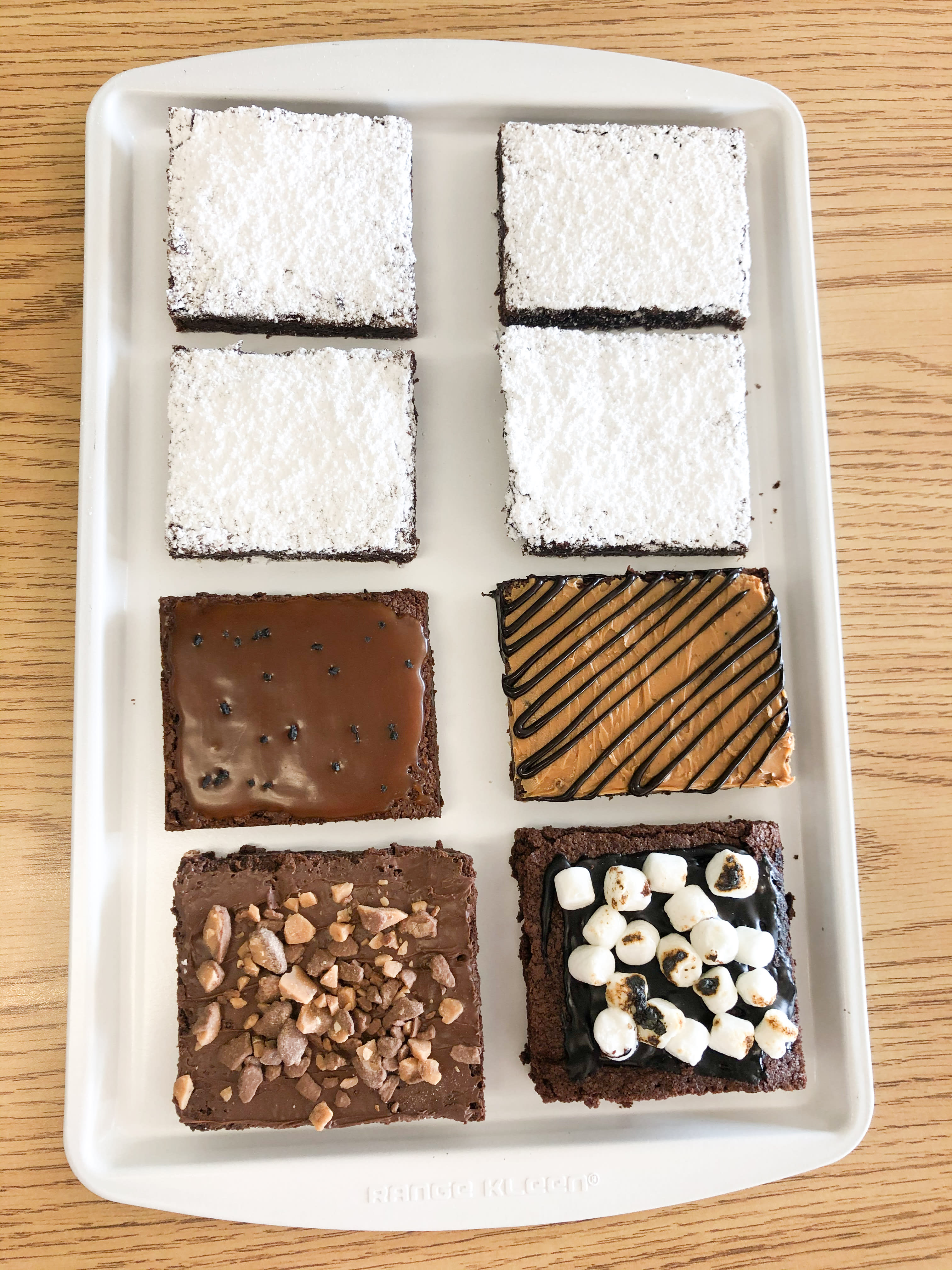 Assorted decorated chocolate brownies arranged on a white tray