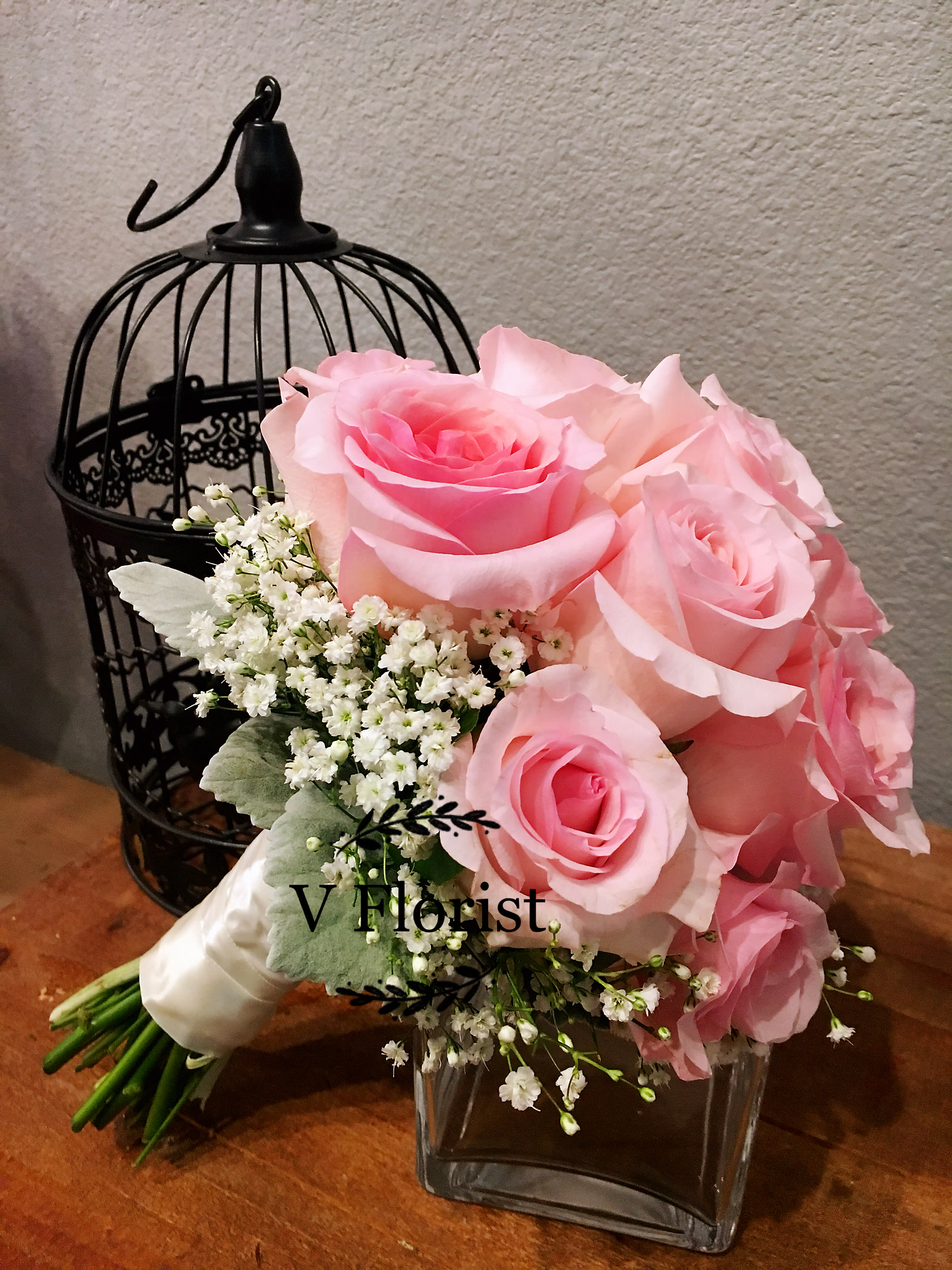 Pink rose bouquet with white filler flowers in a glass vase