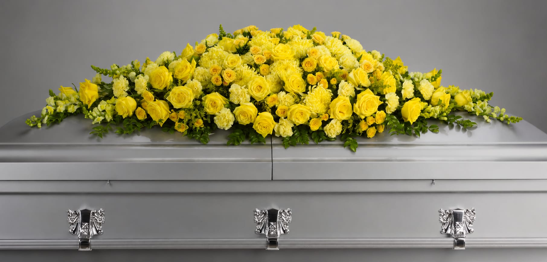 Yellow floral spray arranged on a silver casket