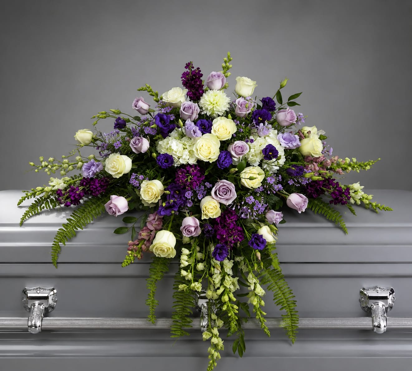 Purple and white floral casket spray with cascading blooms