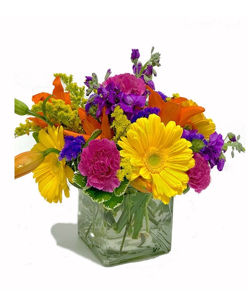 Bright mixed bouquet in a square glass vase