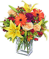 Colorful bouquet of lilies, roses, and daisies in a glass vase
