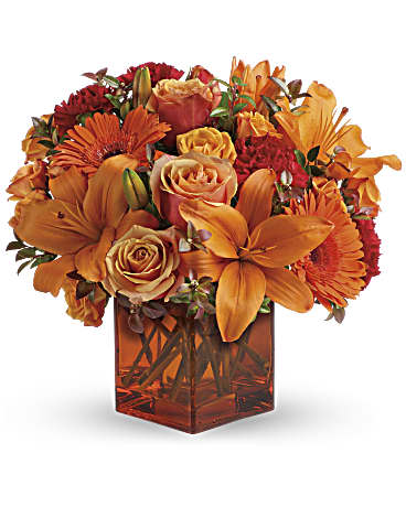 Orange and red bouquet in a square glass vase