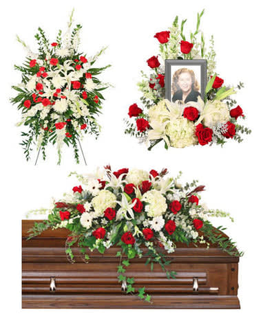 Funeral floral tributes with red and white flowers around a casket and framed photo