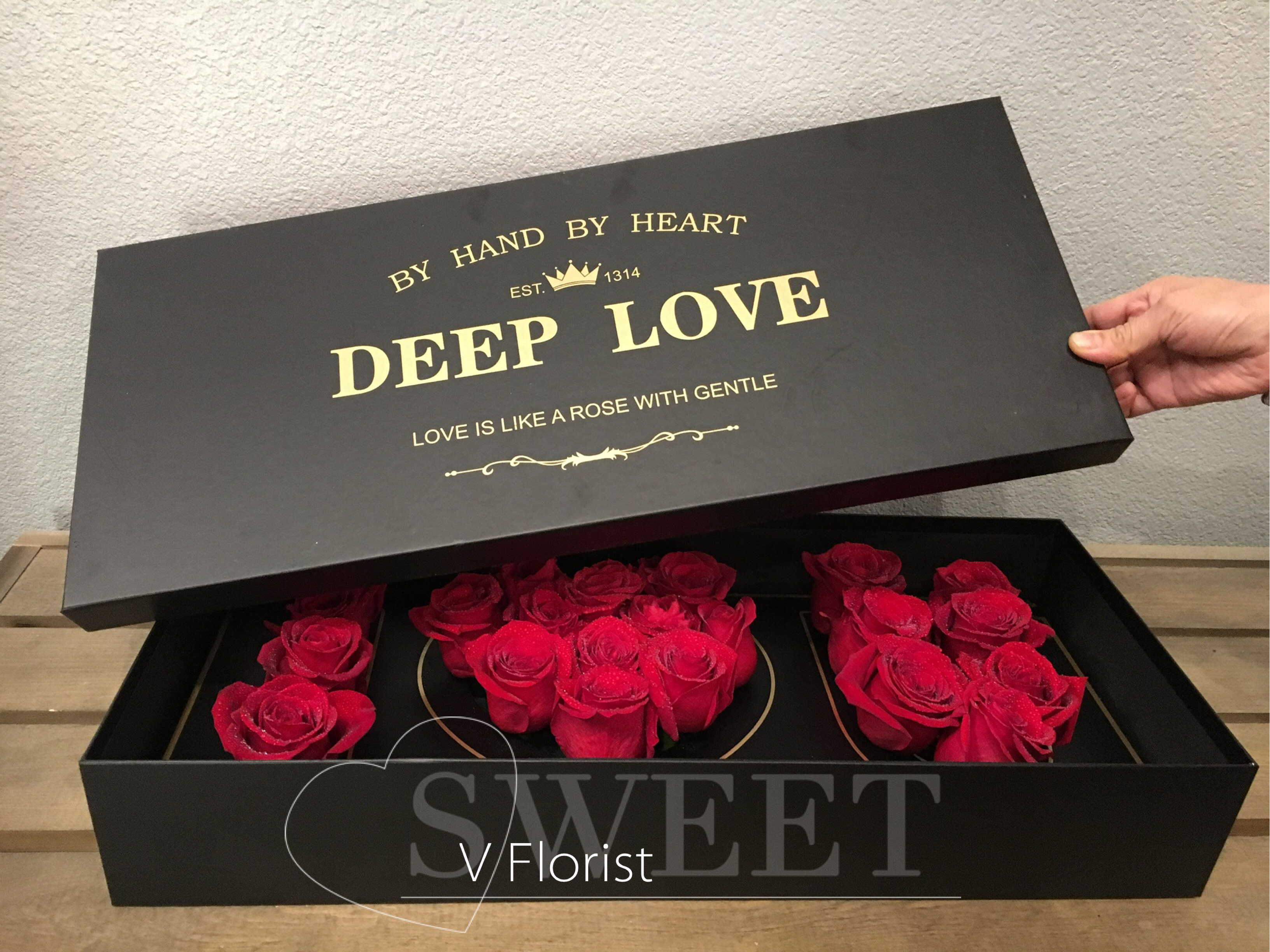 Black gift box with red roses arranged inside