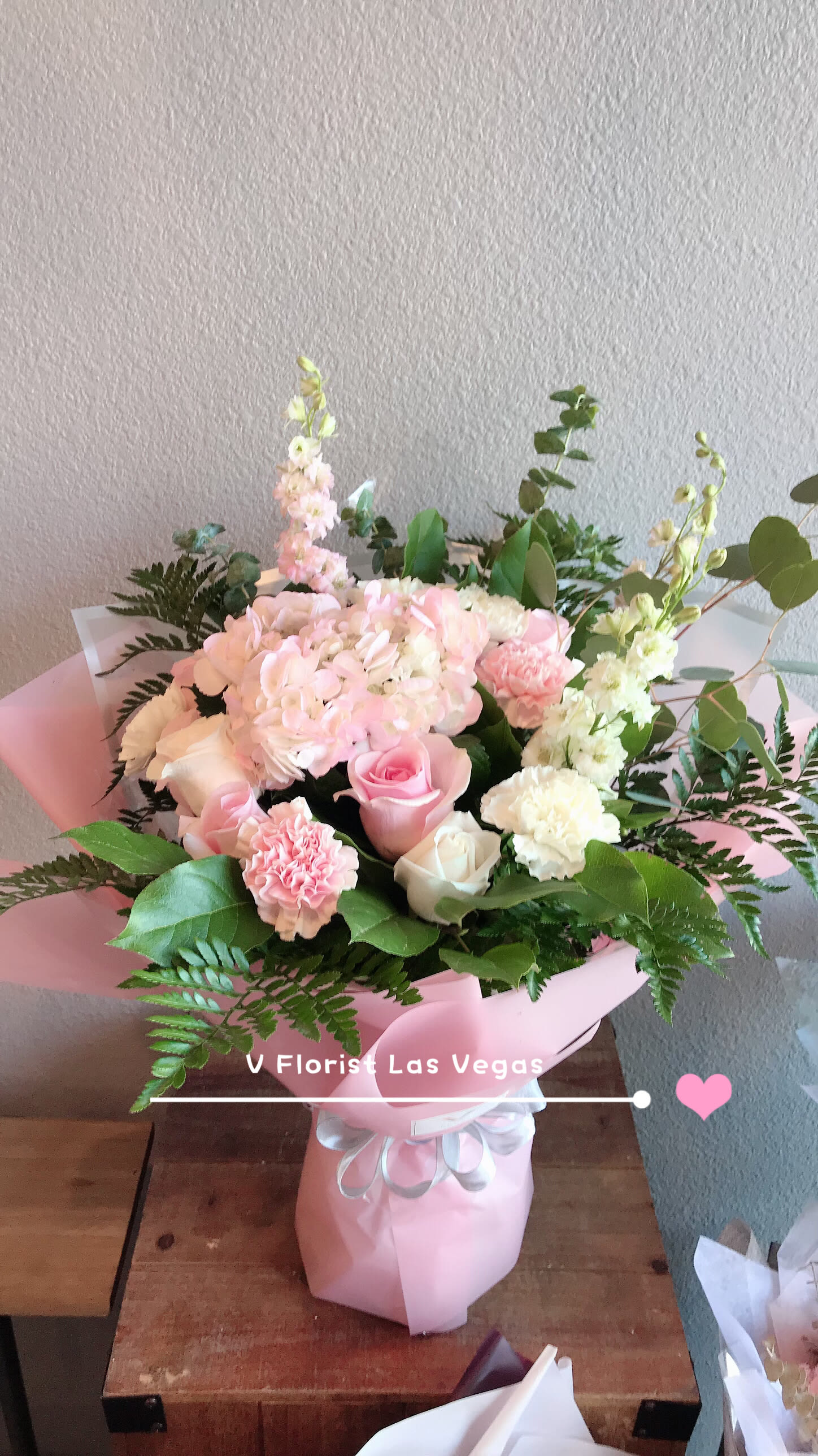 Pink and white bouquet with roses, hydrangea, and carnations in pink wrap