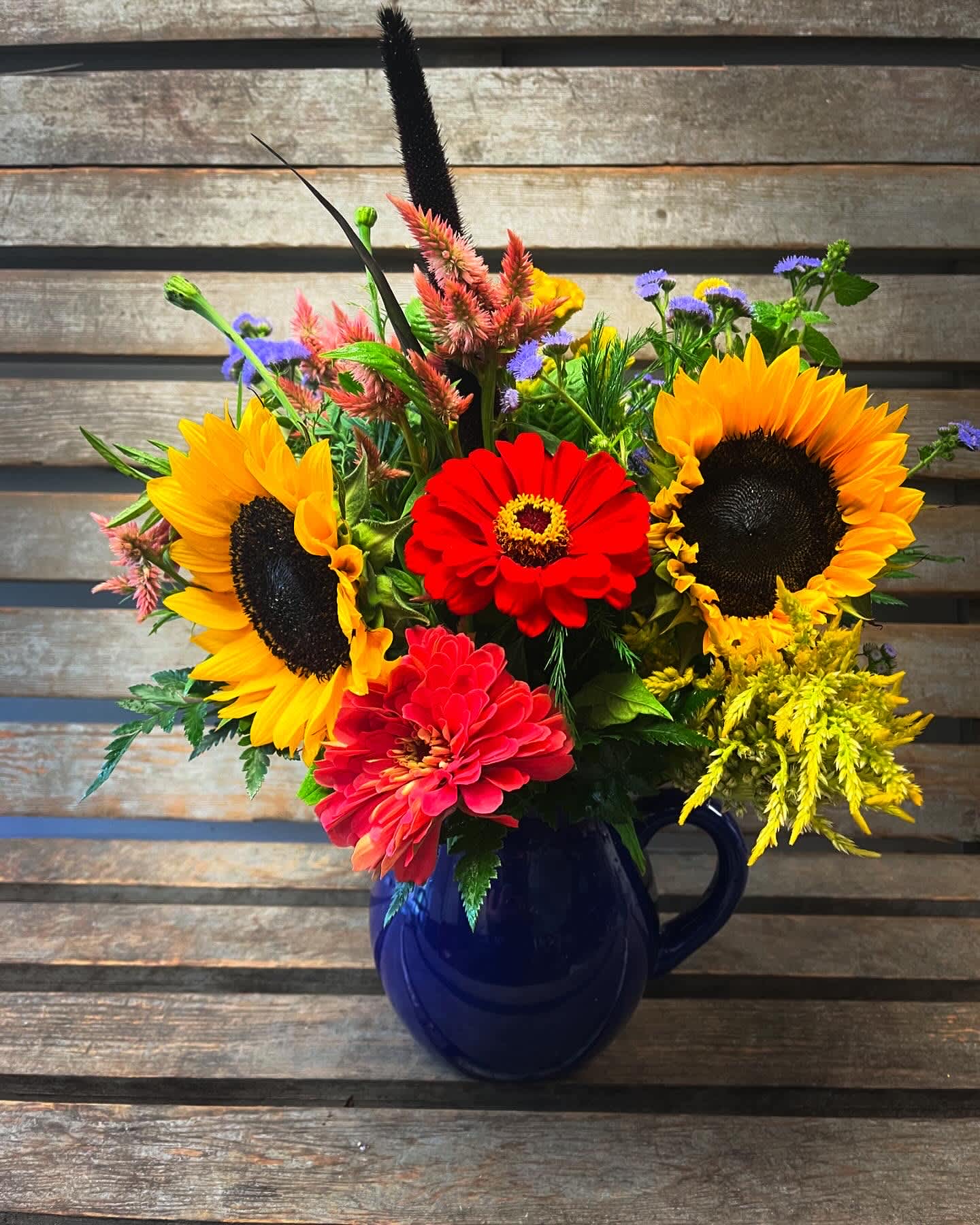 Bright mixed bouquet with sunflowers and zinnias in a blue mug