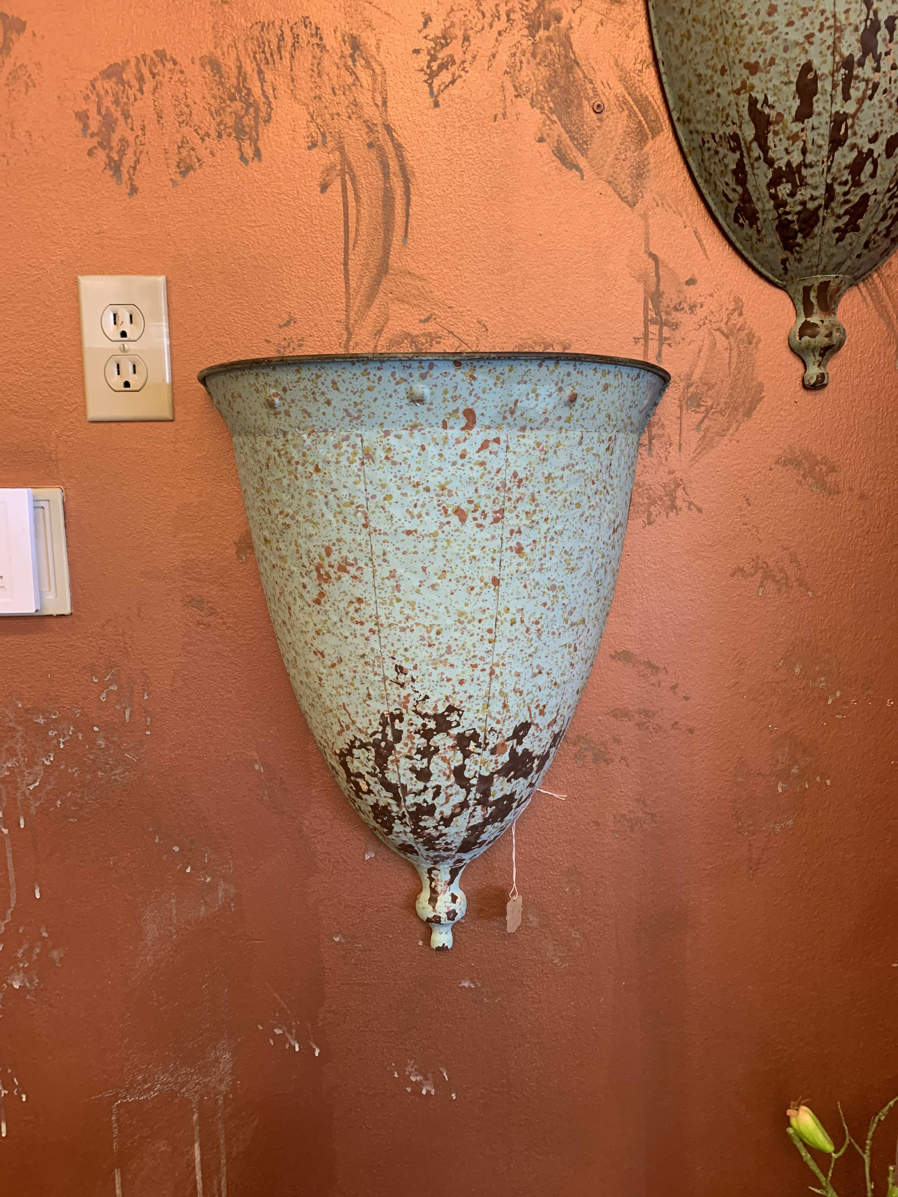 Rustic metal wall planter mounted on an orange wall