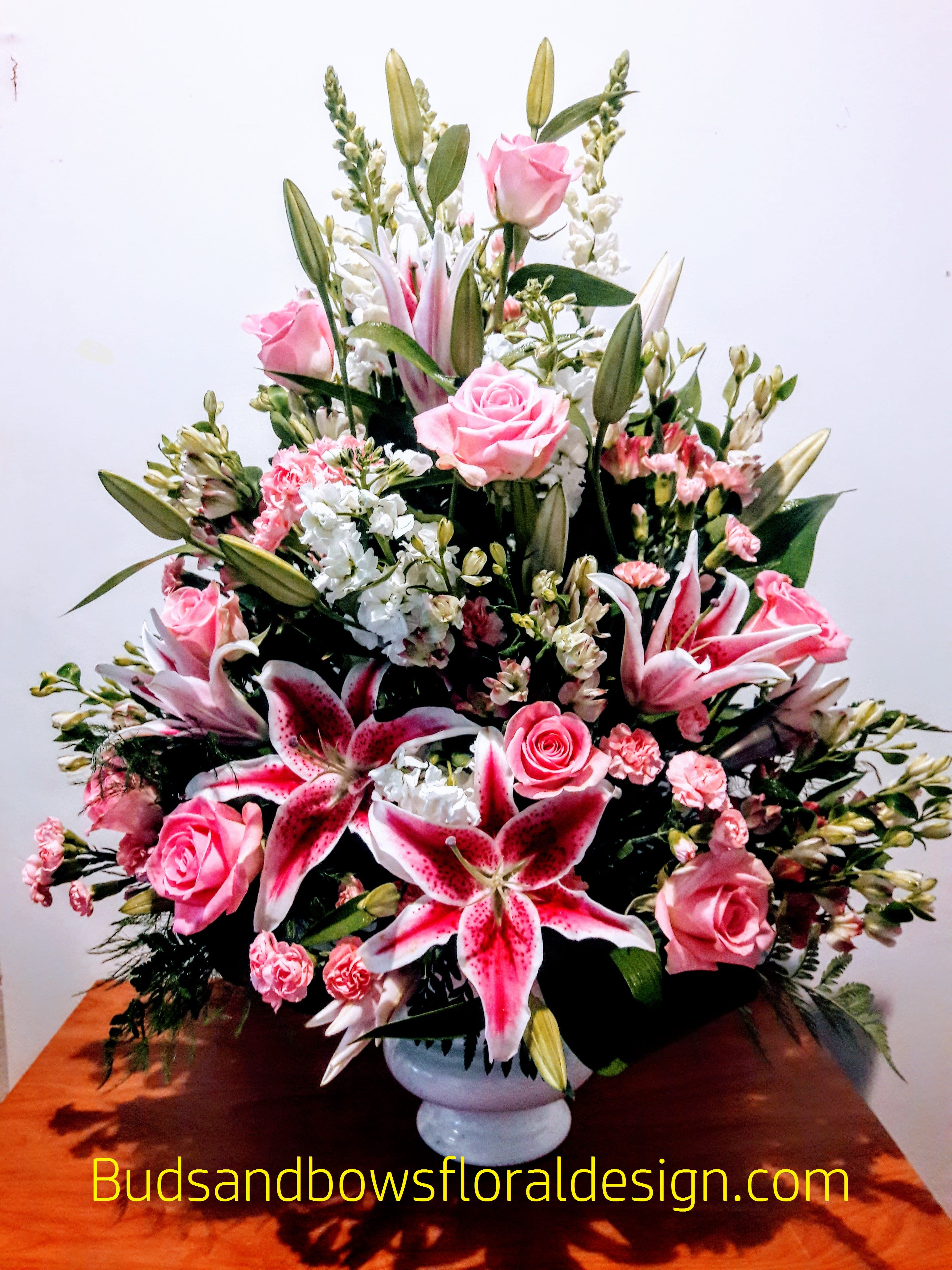 Pink roses and lilies arranged in a white vase