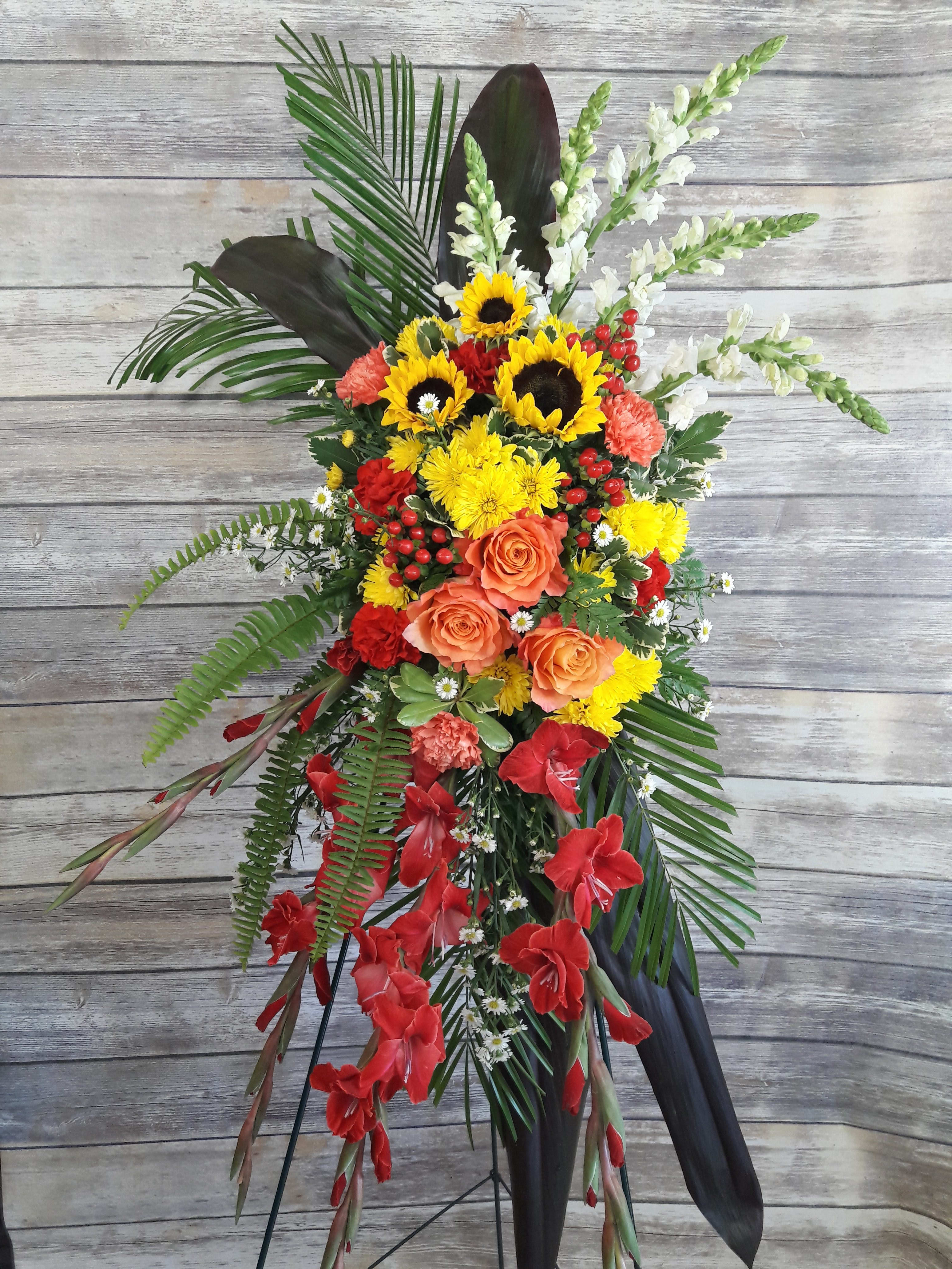 Standing floral spray with sunflowers, roses, and red gladiolus
