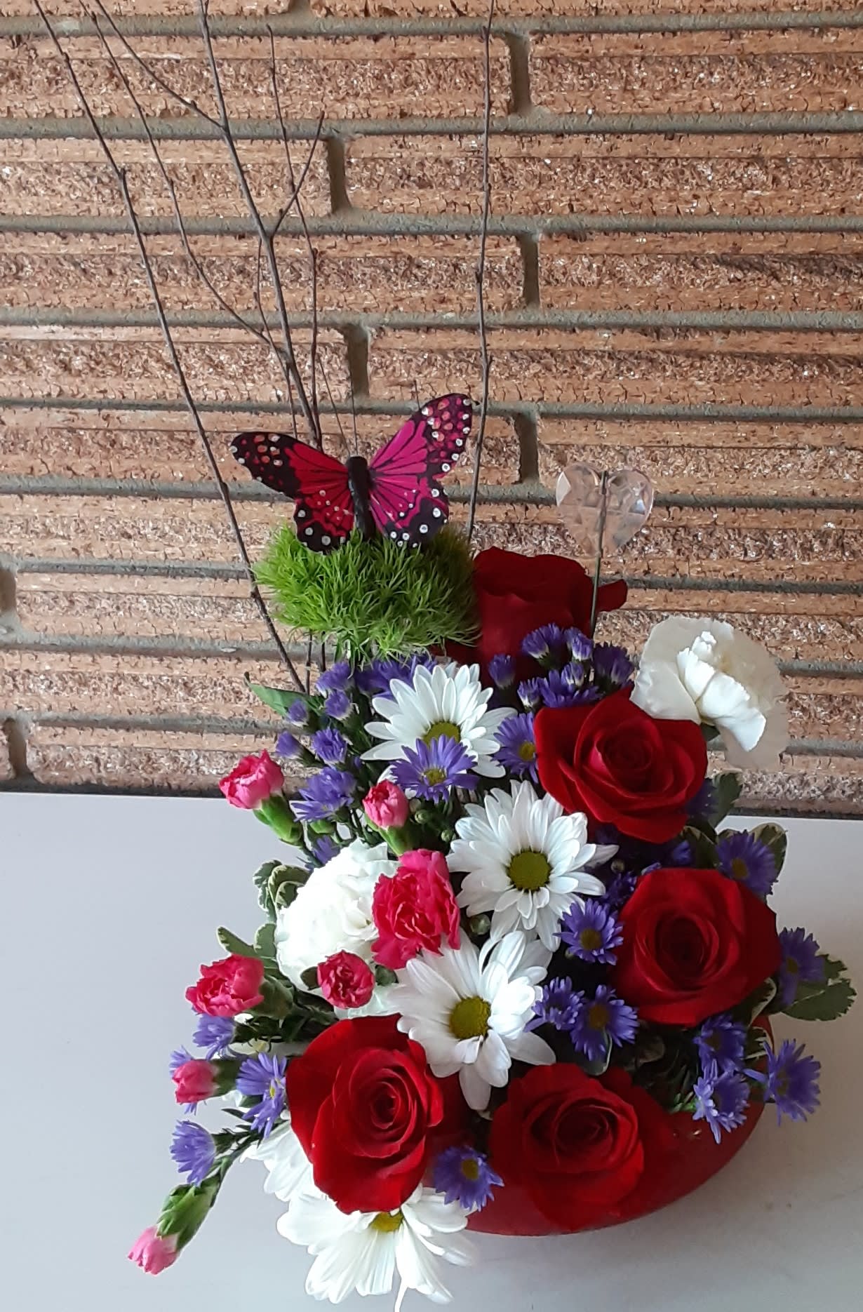 Bouquet of red roses, white daisies, and purple flowers with butterfly picks