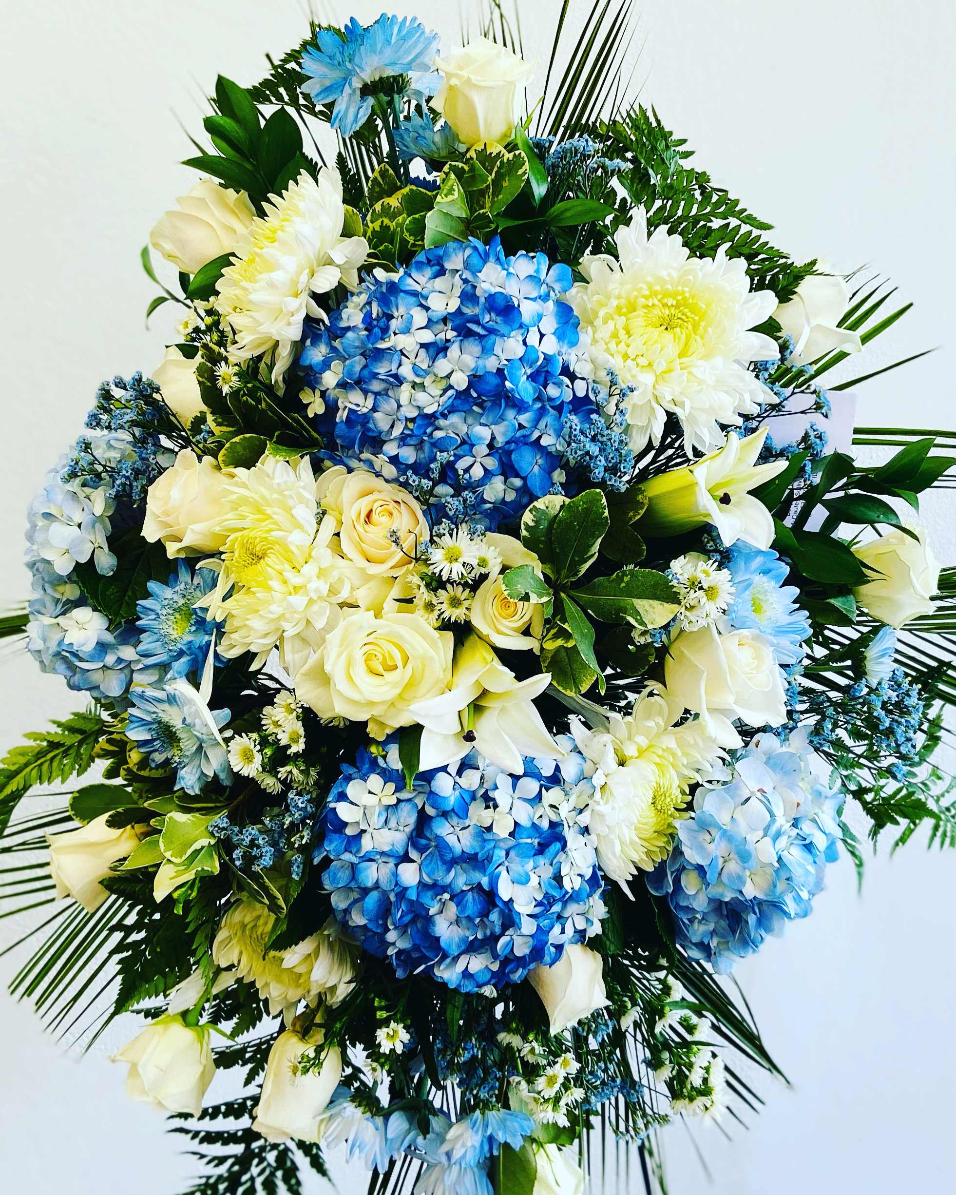 Blue and white floral spray with roses, hydrangeas, and chrysanthemums