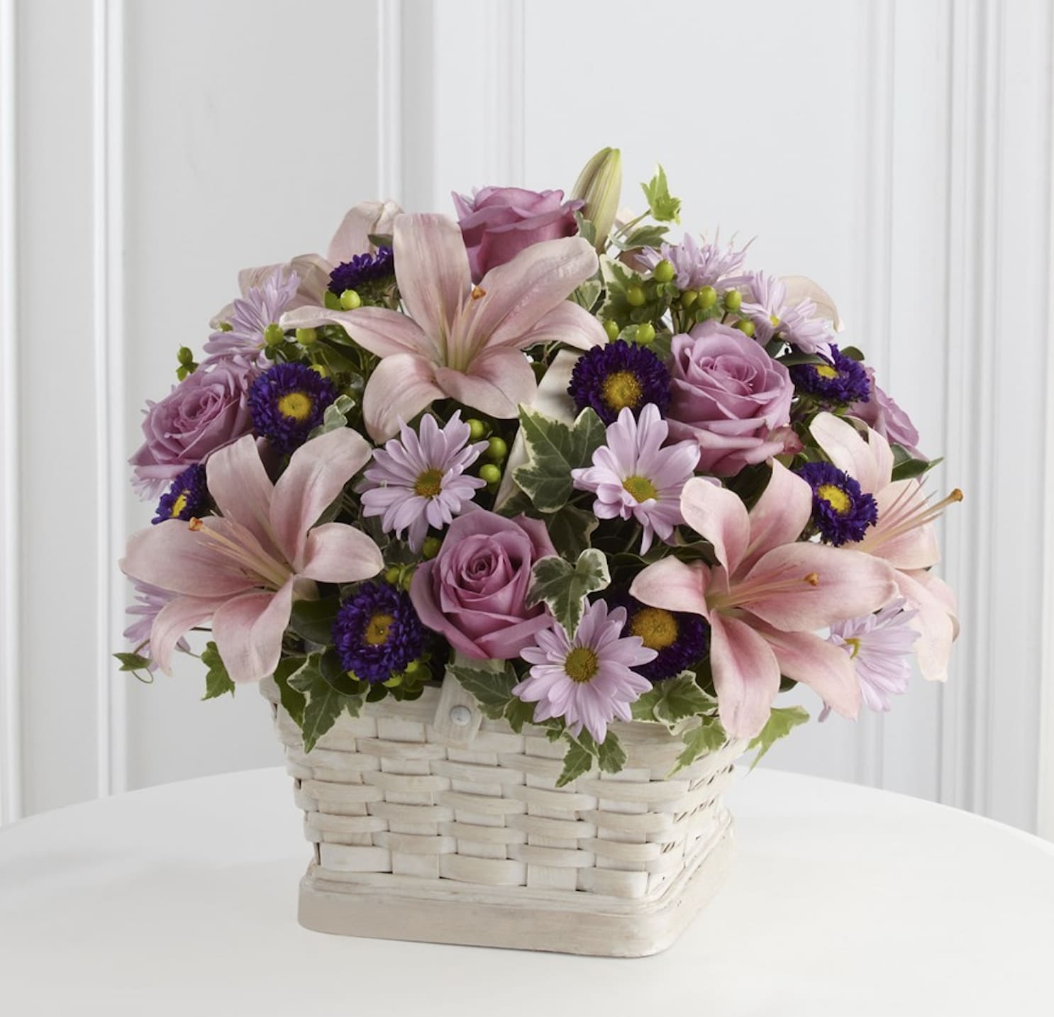 Loving Sympathy Basket - Standard (Shown) = Approx. 14"H x 16"W. Deluxe = Approx. 15"H x 17"W. Premium = Approx. 16"H x 20"W. The FTD Loving Sympathy Basket is a wonderful way to convey your condolences for their loss. Lavender roses, pink Asiatic lilies, lavender daisies, purple matsumoto asters, green hypericum berries and lush greens are sweetly arranged in a square whitewash basket to create a lovely way to offer you caring kindness during this trying time.