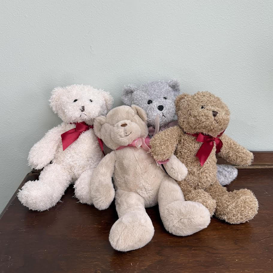 Four teddy bears with ribbon bows sitting on a table