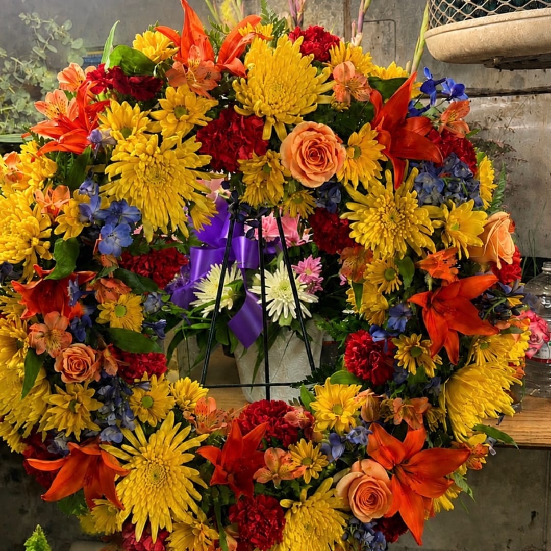 Colorful floral wreath with yellow mums, orange lilies, and peach roses