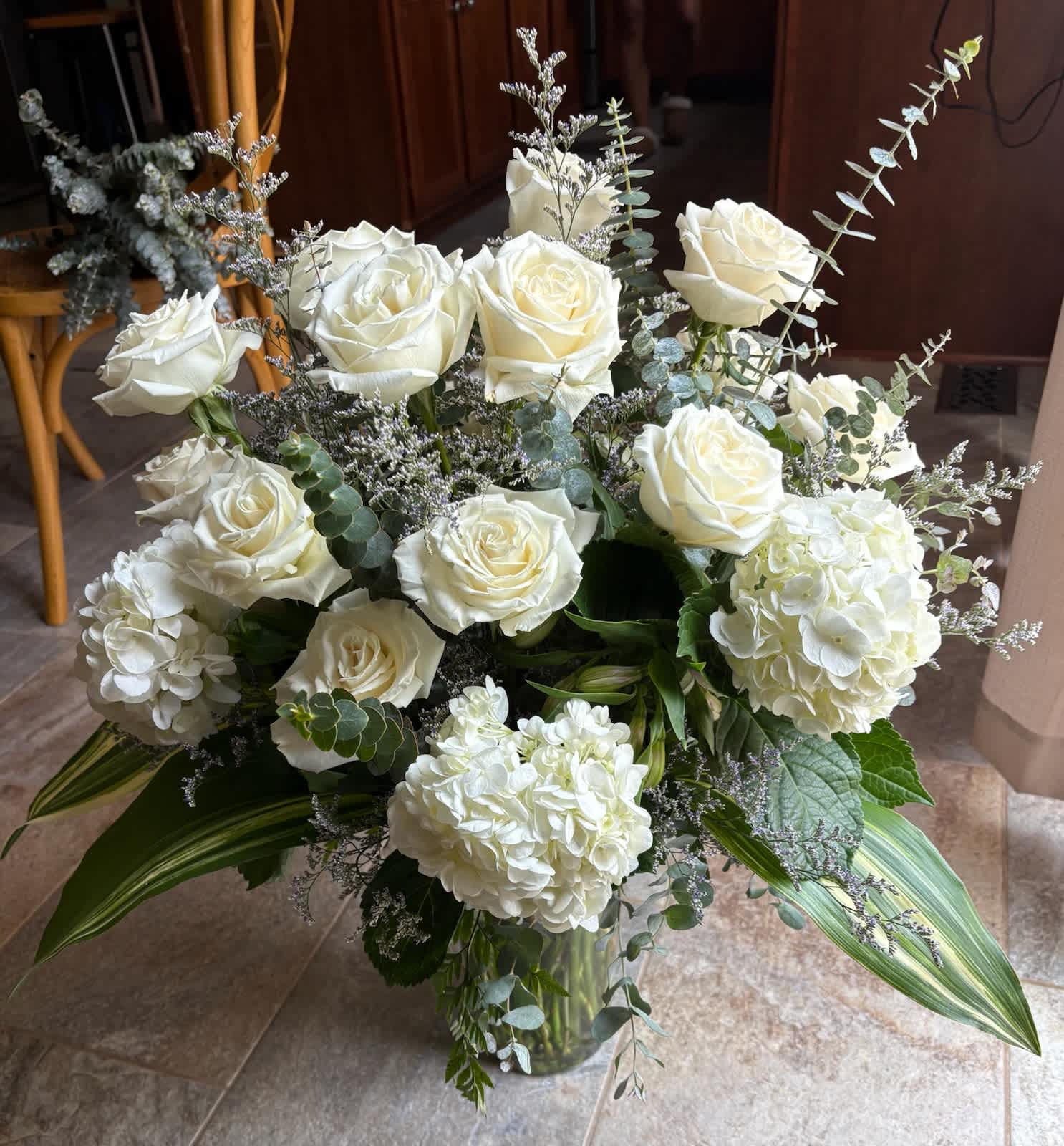 White roses and hydrangeas arranged in a glass vase