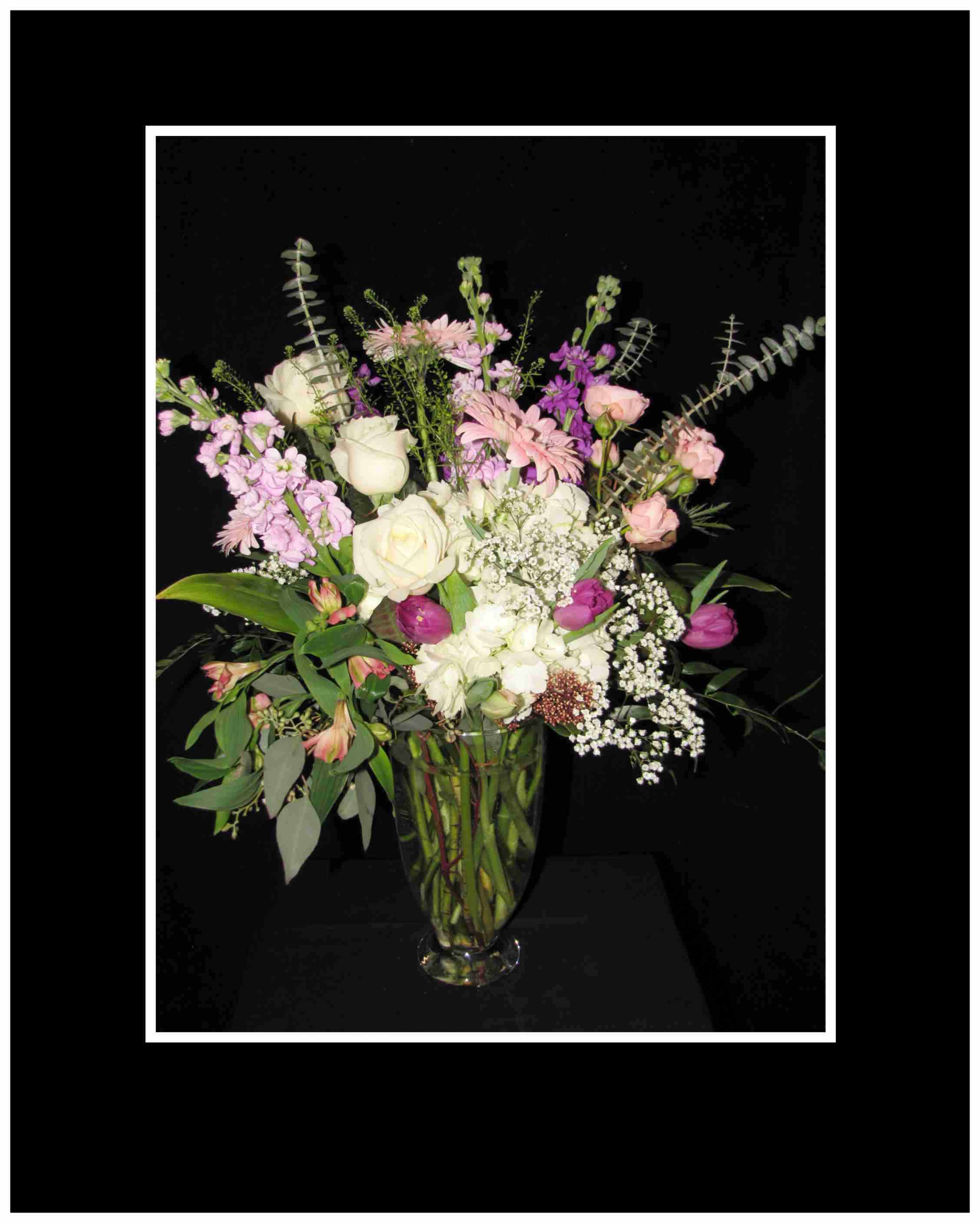 Mixed pink and white flowers arranged in a clear glass vase