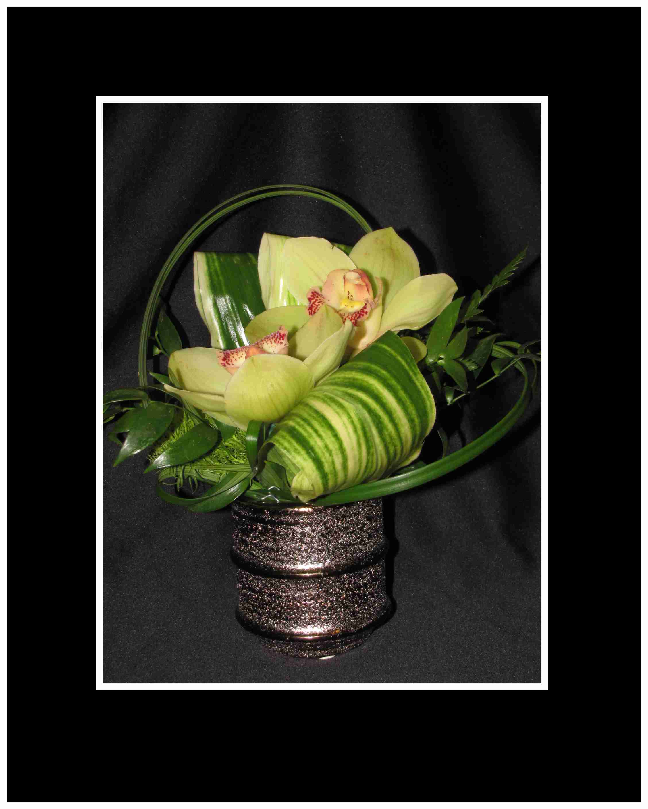 Orchid arrangement in a glittery basket with green foliage