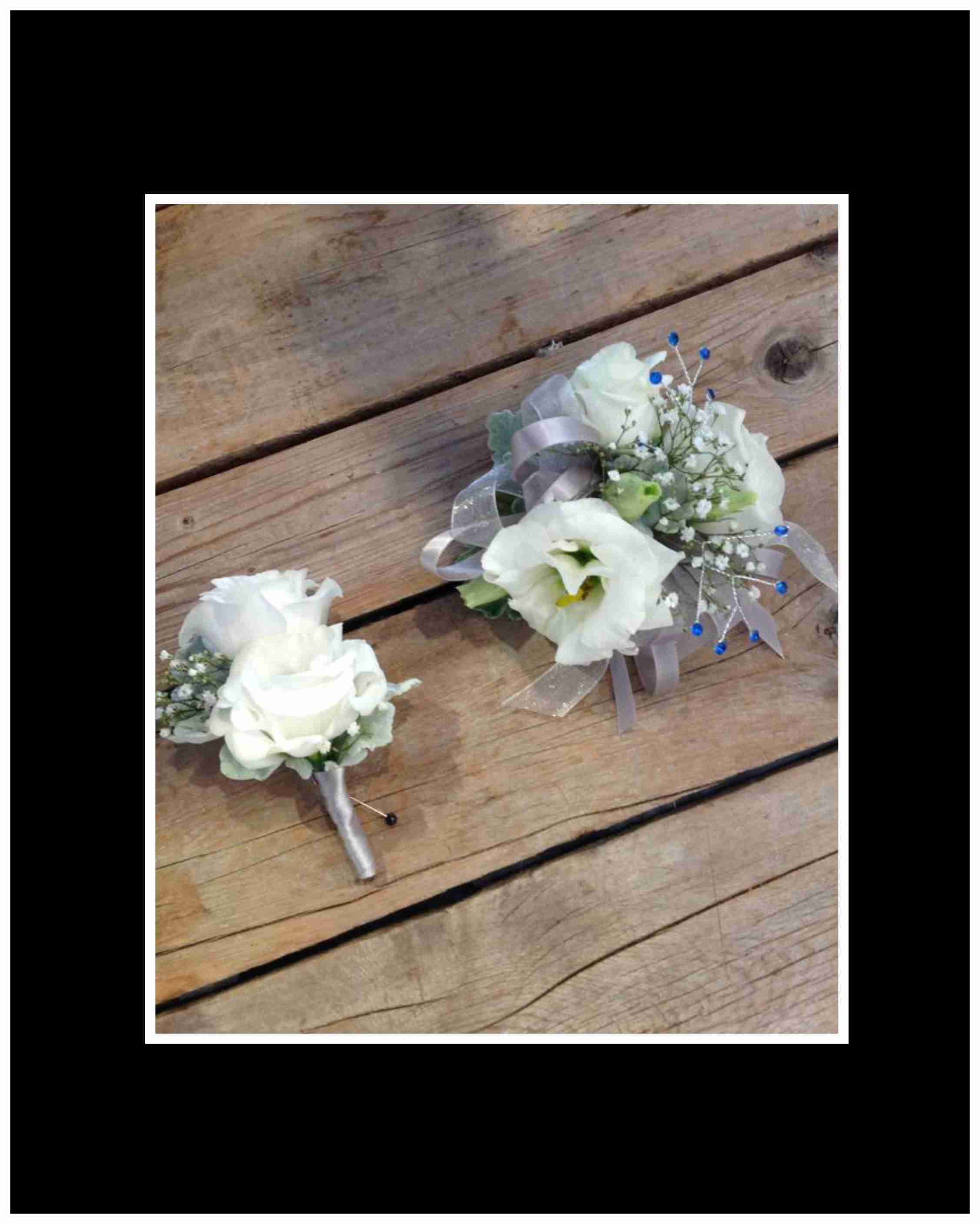White floral corsage and boutonniere with ribbon on wood