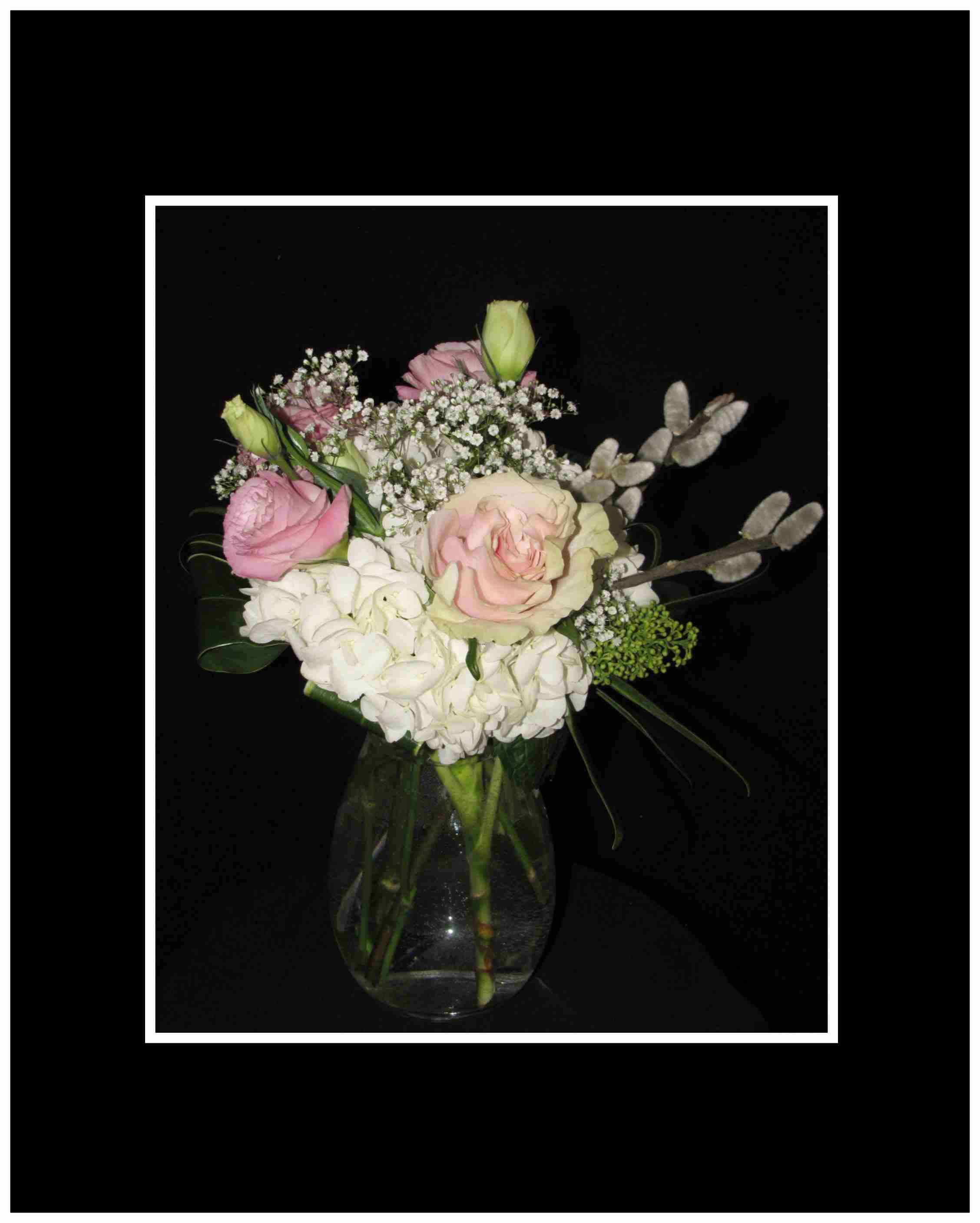 Pink and white roses with hydrangea in a clear glass vase