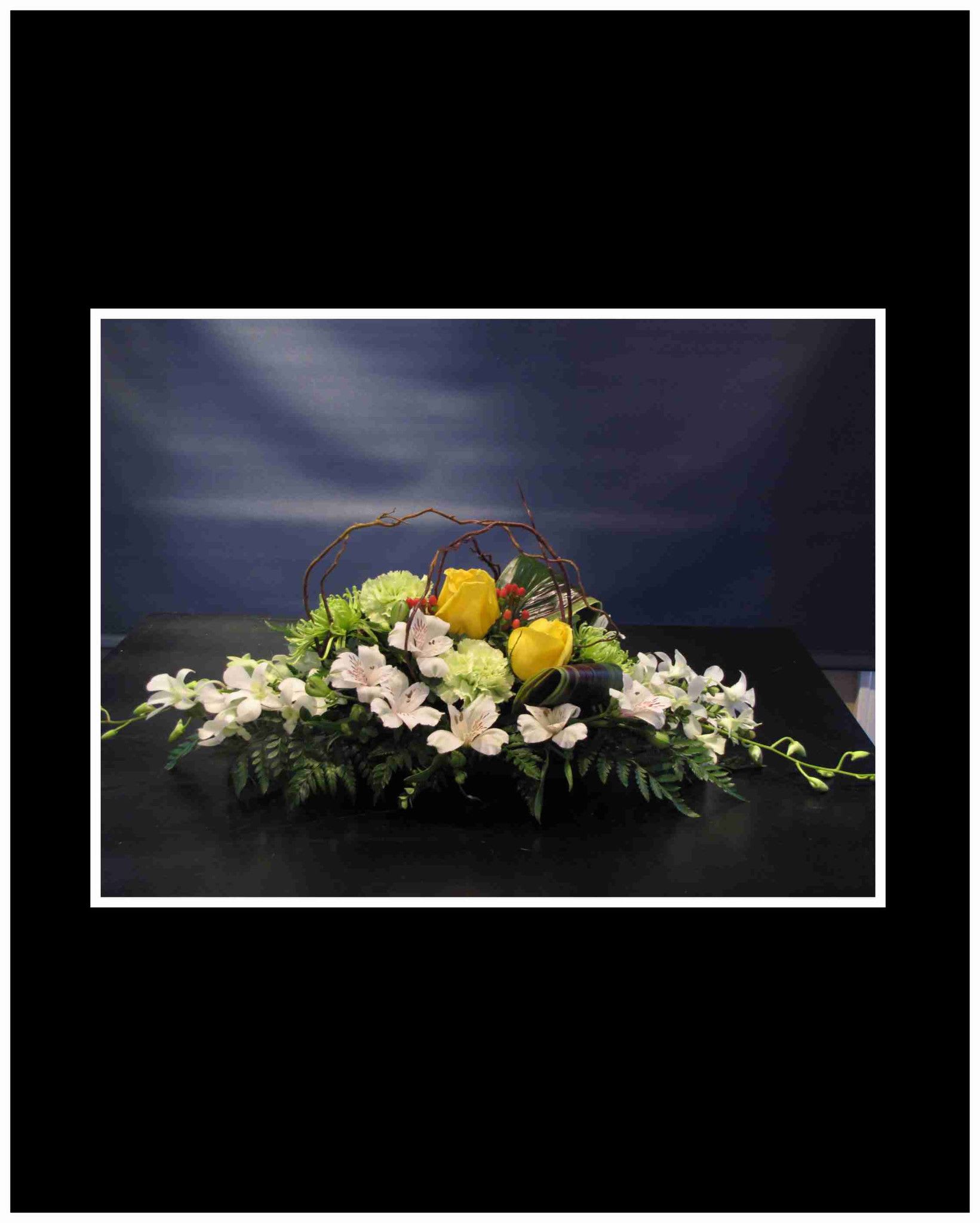 Low floral centerpiece with yellow roses and white orchids