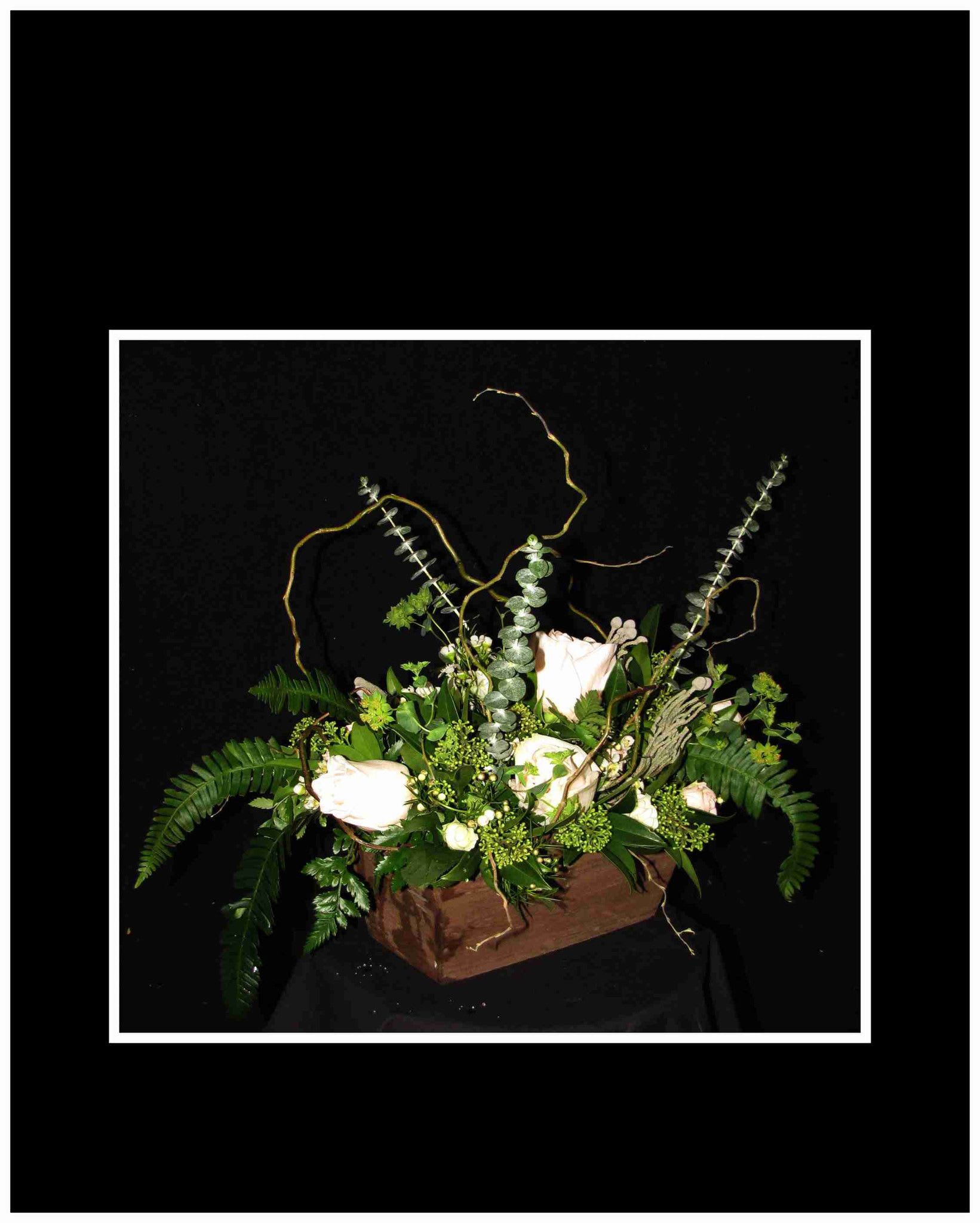 White roses in a rustic wooden box with greenery and curly branches