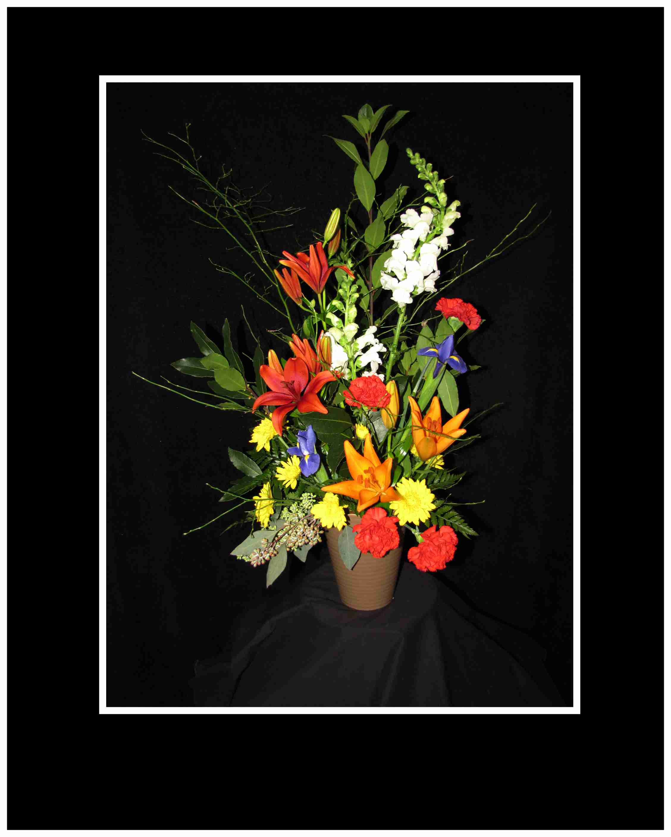Tall mixed flower arrangement in a brown vase