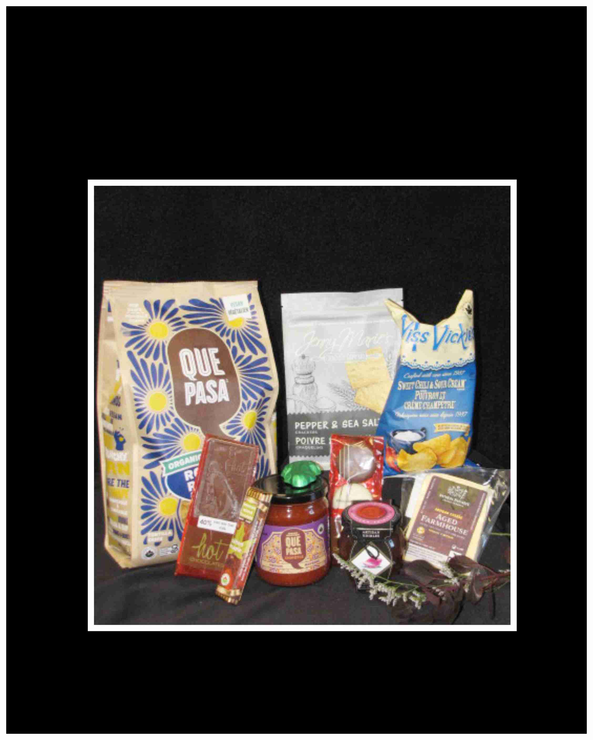 Assorted snack and chocolate gift items arranged on a dark background