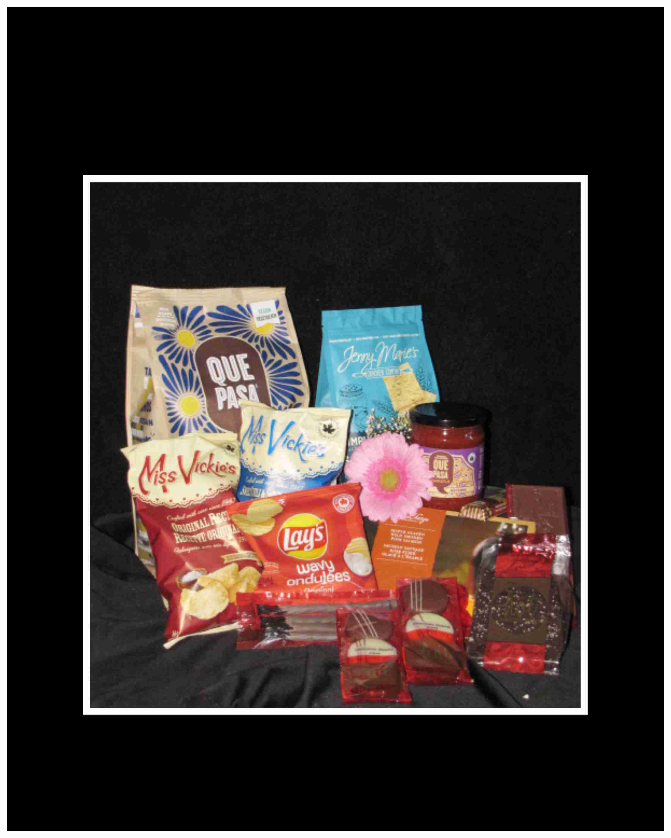Assorted snack and candy gift basket with a pink flower accent