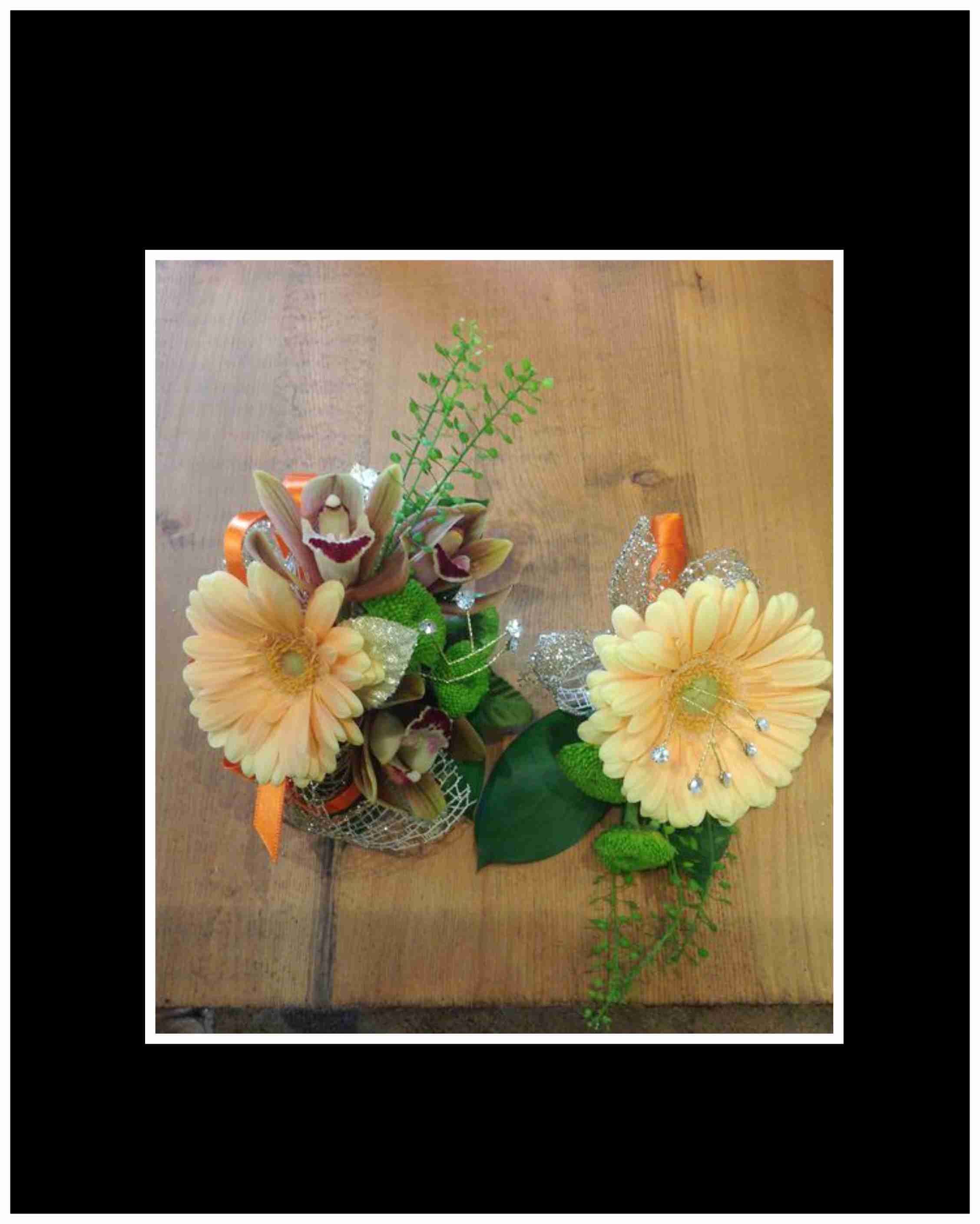 Two floral corsages with pale yellow blooms and orange ribbon accents