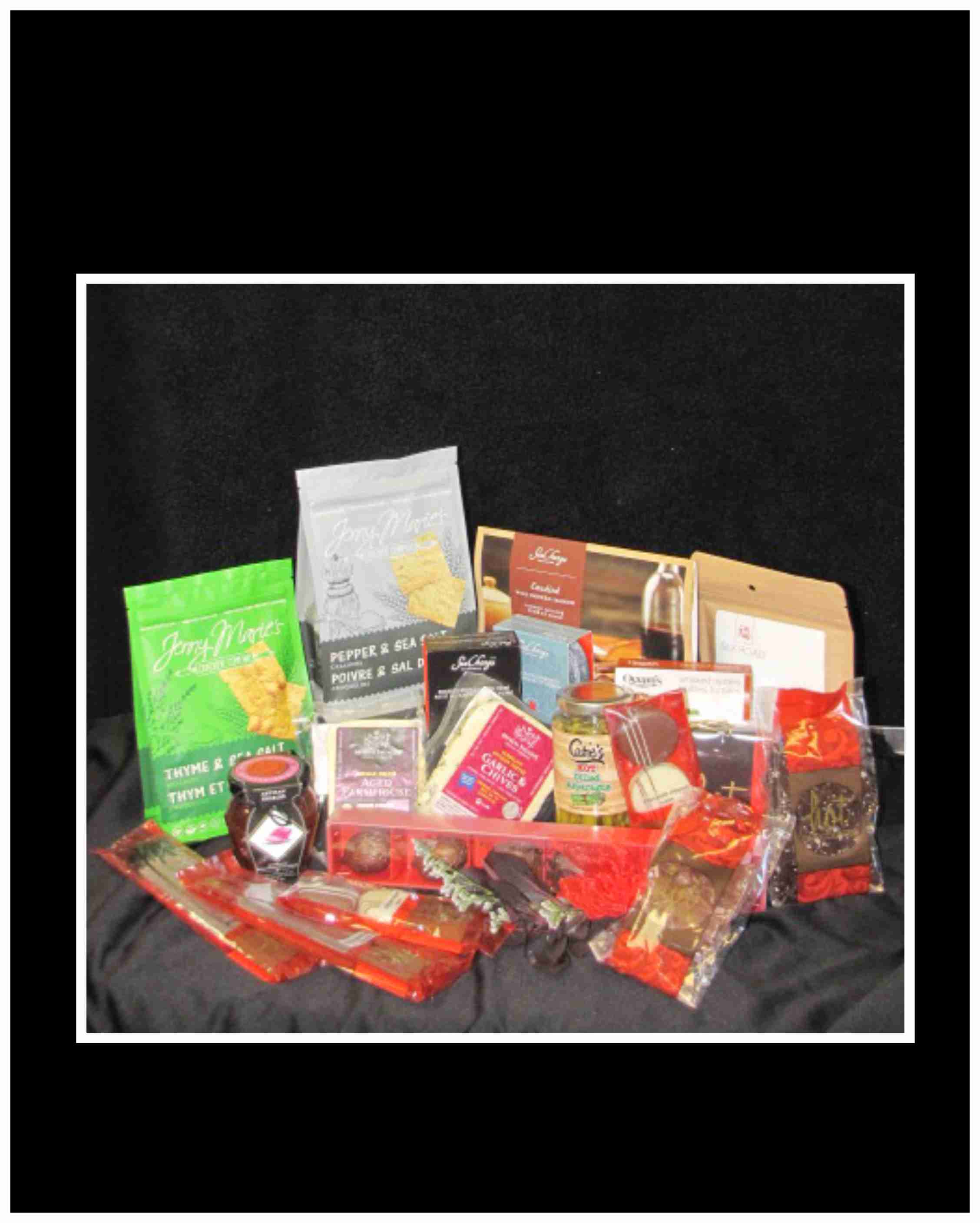 Assorted gourmet snack and candy gift basket on black fabric