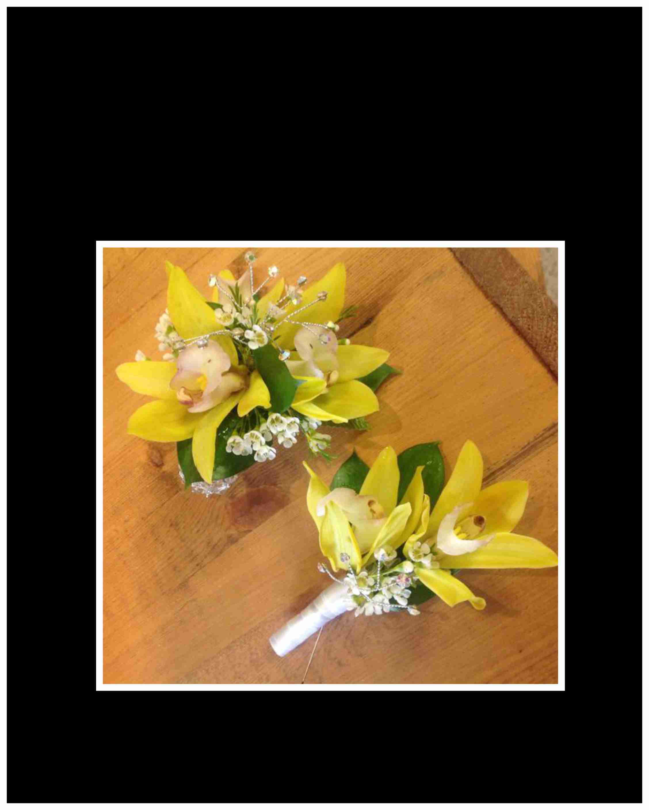 Two yellow orchid boutonnieres with white ribbon and small white accents