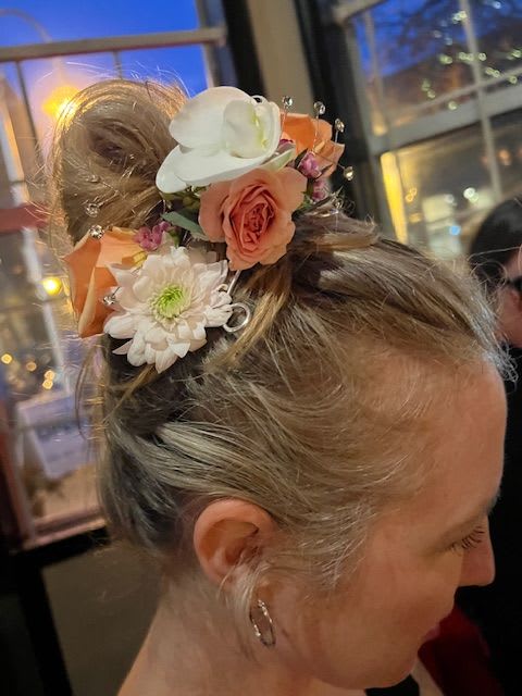 Floral hairpiece with white orchids, peach roses, and white daisies