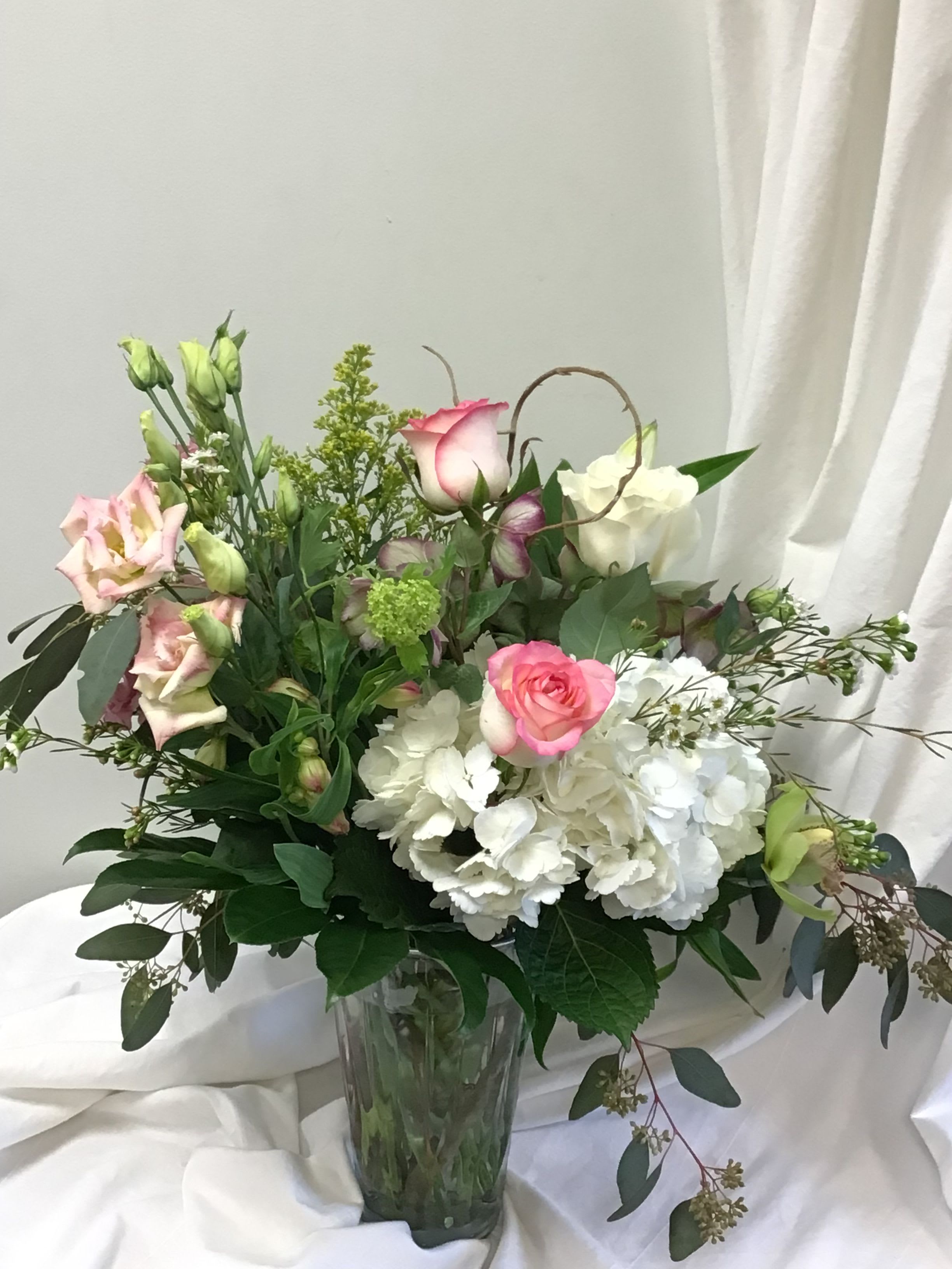 Pink and white roses with white hydrangeas in a glass vase