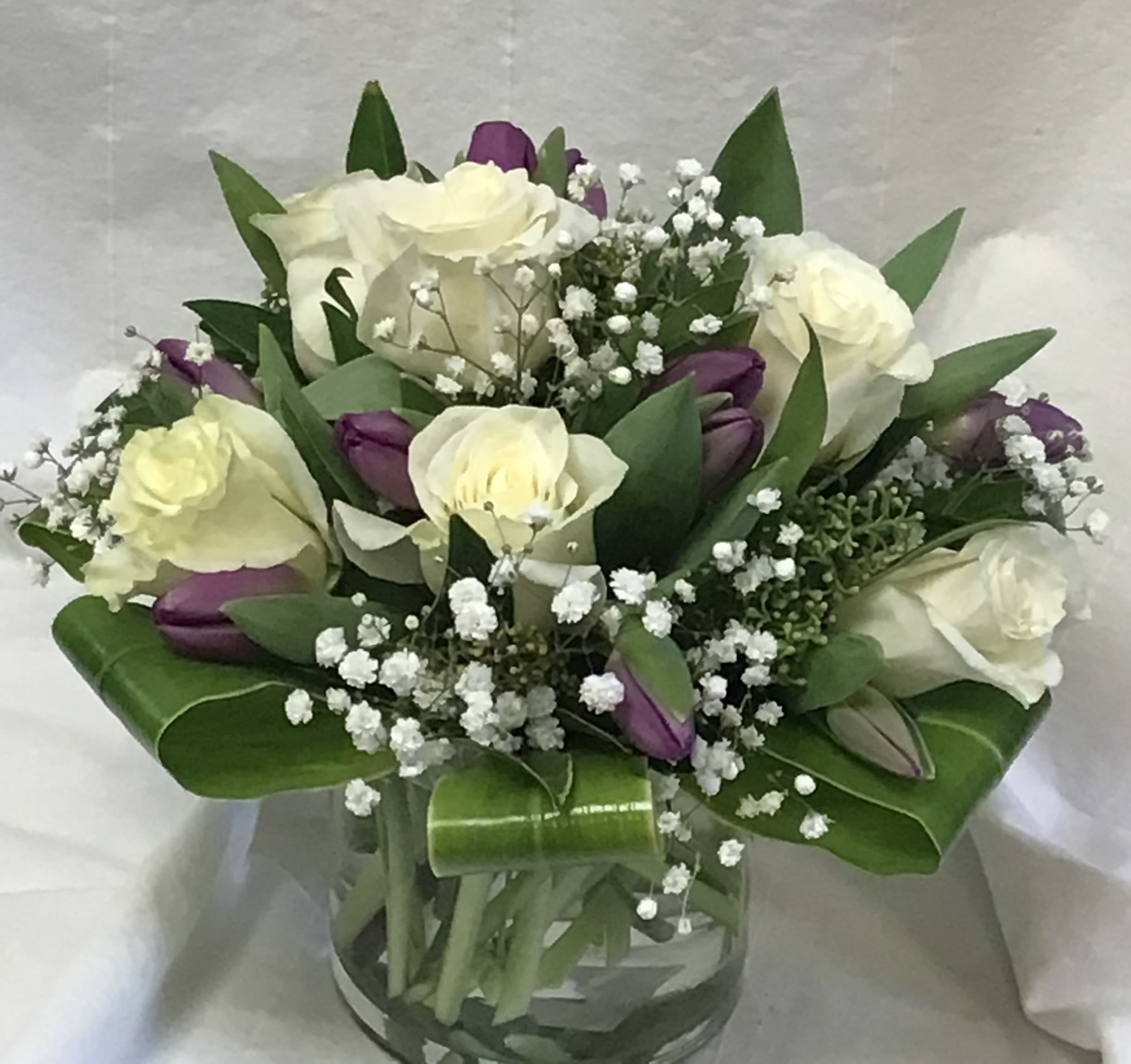 Bouquet of white roses and purple tulips in a glass vase