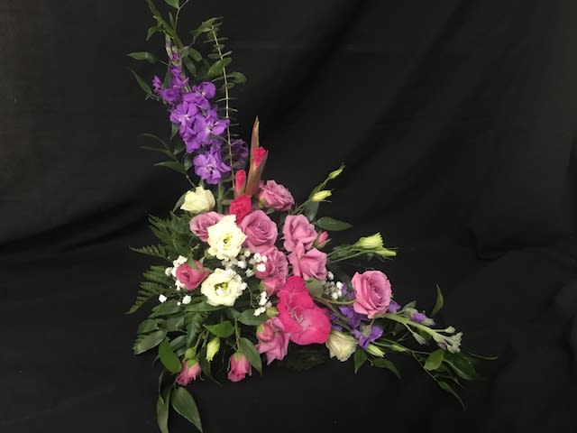 Pink and white floral arrangement with purple flowers on a black background