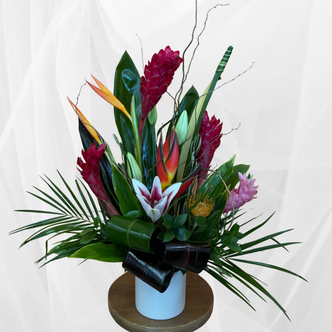 Tropical flower arrangement in a white vase with red and pink blooms