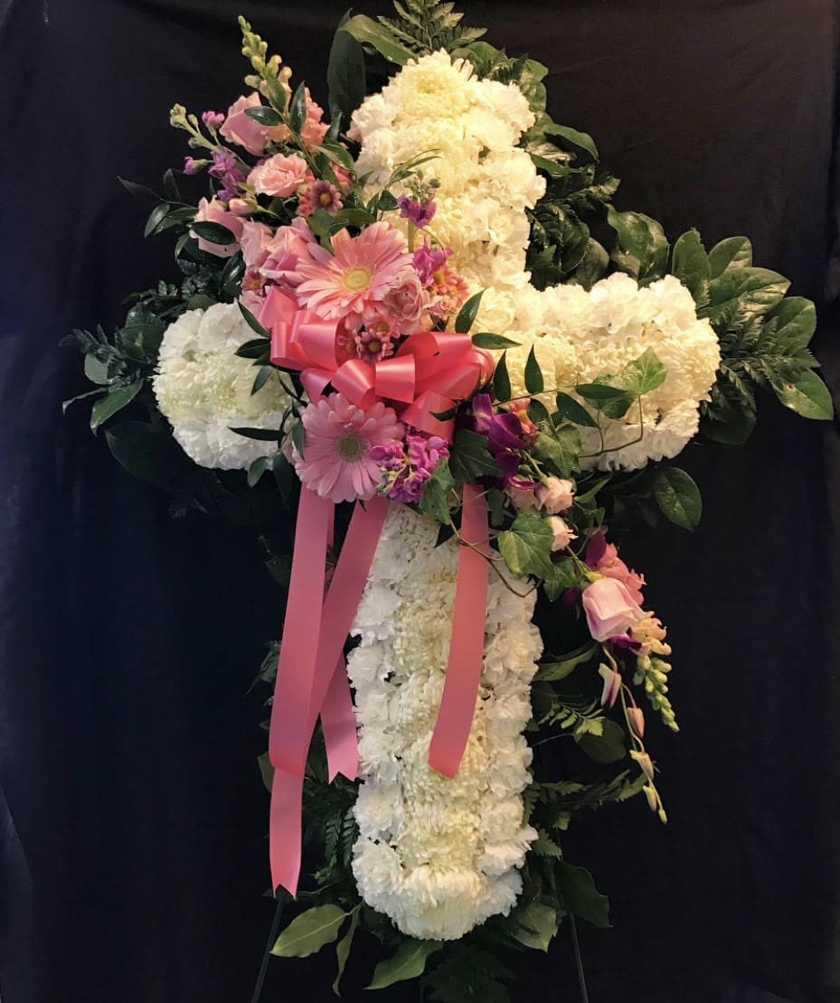Standing floral cross with pink and white flowers and a pink ribbon