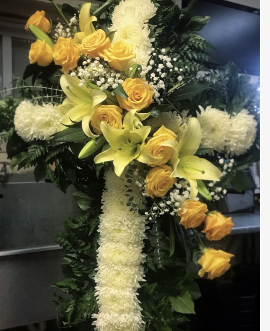 Yellow roses and lilies arranged in a white floral cross