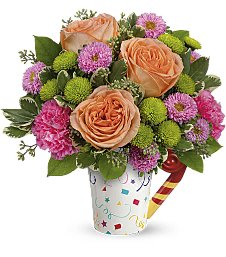 Peach roses and pink flowers in a confetti-patterned cup with a candy cane pick