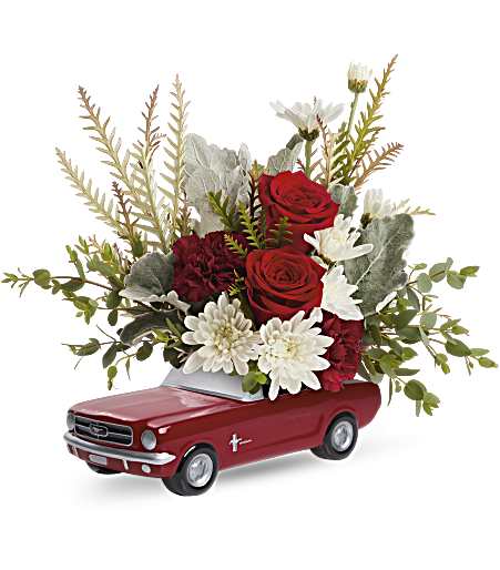 Red roses and white daisies arranged in a red toy car