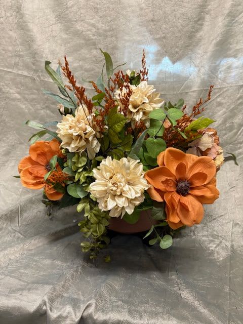 Orange and cream floral arrangement in a low container
