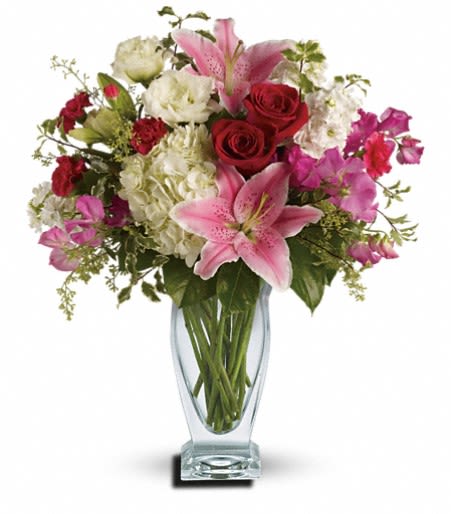 Bouquet of pink lilies, red roses, and white blooms in a glass vase