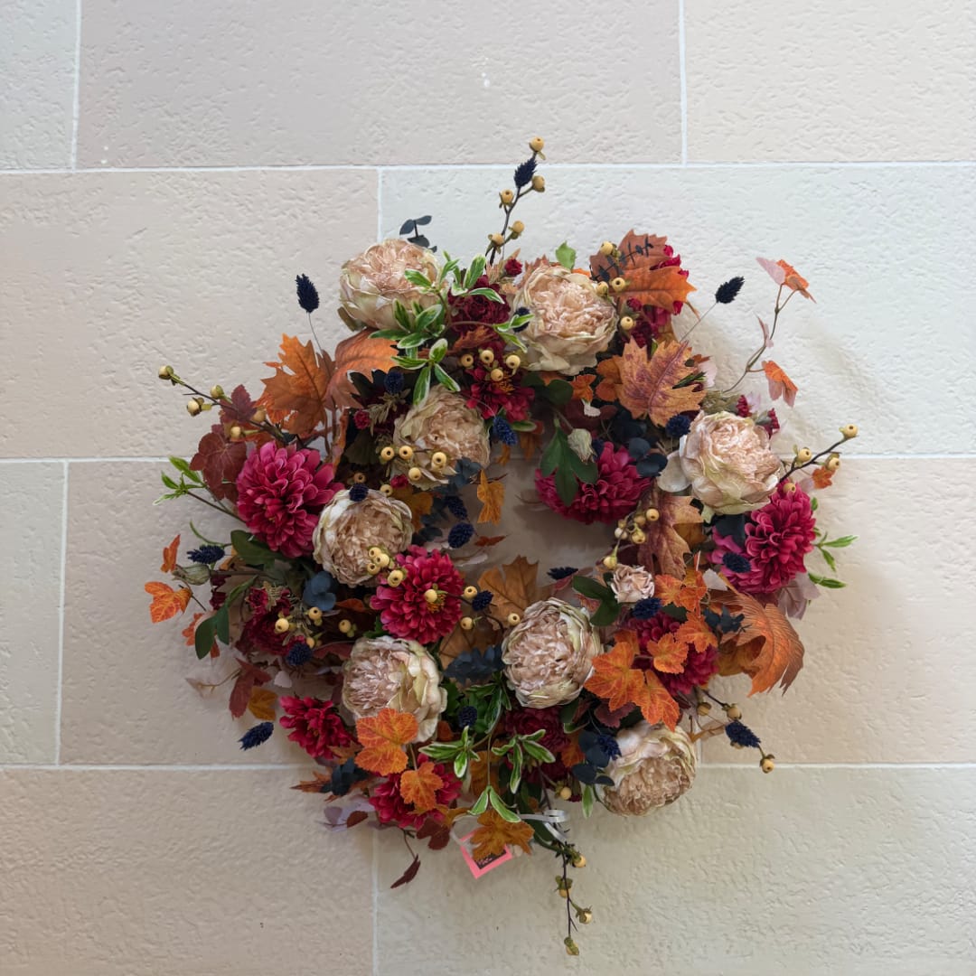 Autumn wreath with pink flowers and beige blooms on a wall