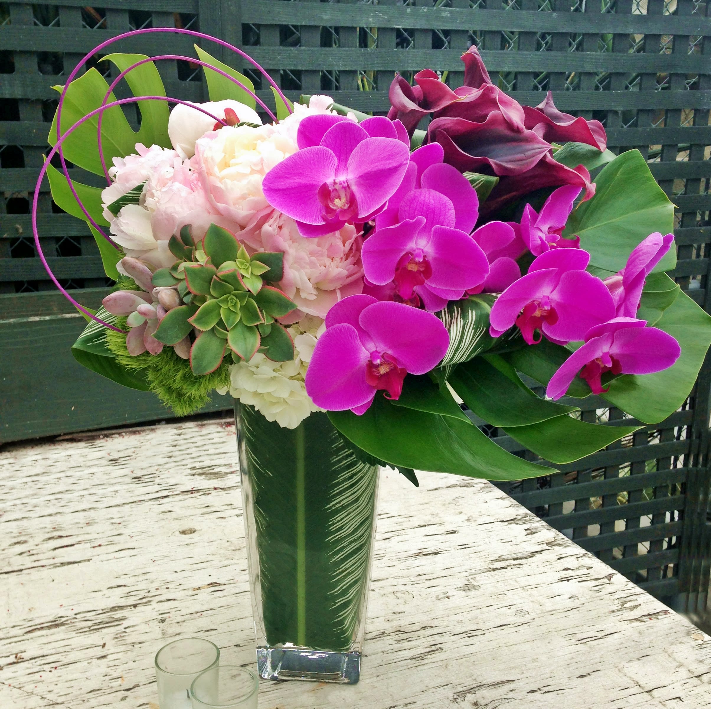 Pink orchids and calla lilies in a tall glass vase