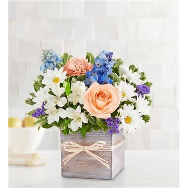 Mixed bouquet in a wooden box with daisies, roses, and blue flowers