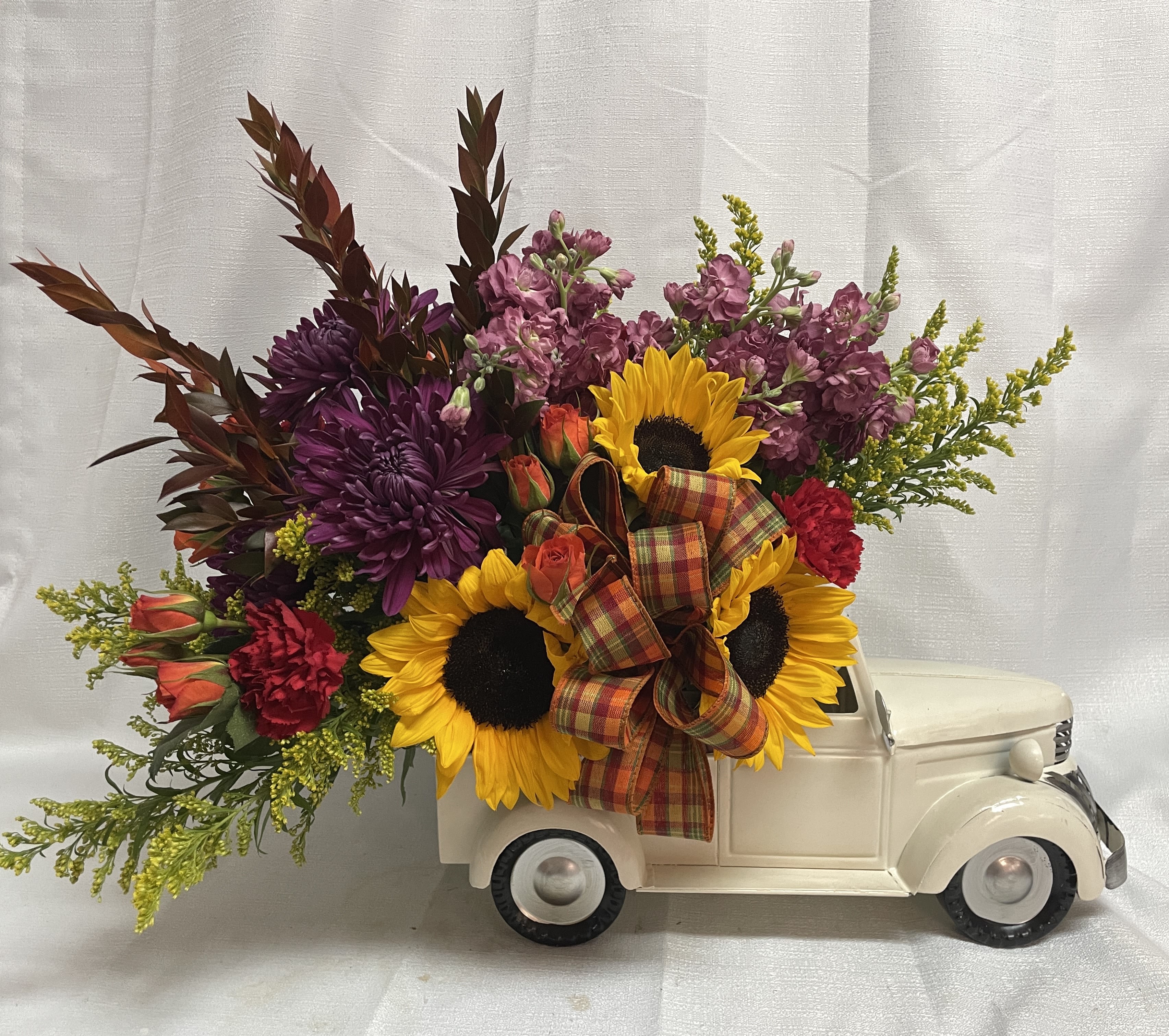 Pumpkin Patch Pickup - Inspired by a classic trip to the pumpkin patch, this arrangement features a charming, vintage-style truck brimming with a vibrant harvest of autumn flowers. It’s a perfect centerpiece for adding rustic elegance and seasonal cheer to any home! Measures 25" long by 20" tall by 15" wide.