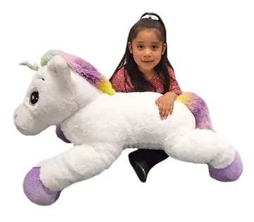 Girl hugging a large white unicorn plush toy with rainbow accents
