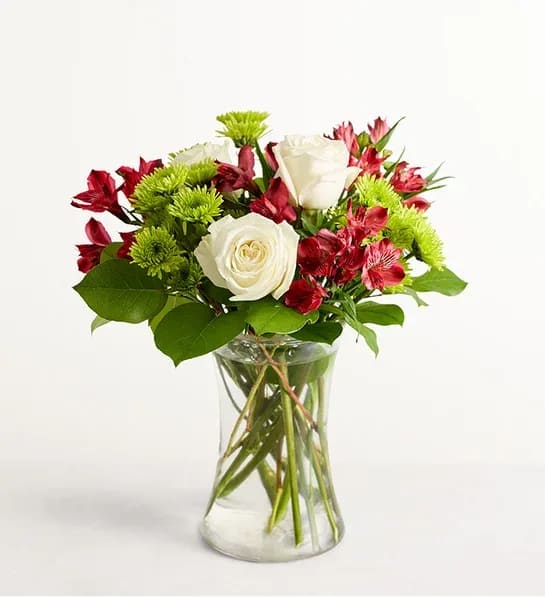 White roses and red alstroemeria in a clear glass vase
