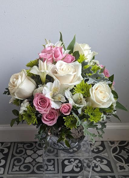 Bouquet of pink and white roses with mixed greenery in a glass vase